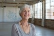 © CogniLens - Portrait of a joyful caucasian woman in her 60s smiling at the camera in empty modern loft background