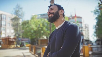 Wall Mural - Bearded man in a sweater laughing outdoors on a sunny day in a city park.