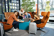 © LIGHTFIELD STUDIOS - Multicultural colleagues in casual attire working together around a table with laptop in a hotel lobby during a corporate trip.