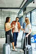 © LIGHTFIELD STUDIOS - Multicultural colleagues on a corporate trip stand with luggage in a hotel lobby, ready for their journey.