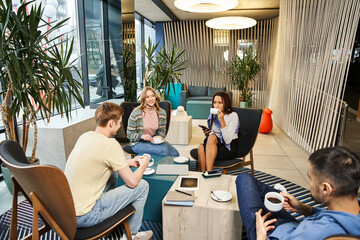 Wall Mural - A diverse group of colleagues in a coworking space engages in discussions and collaboration in a contemporary living room setting.