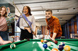 © LIGHTFIELD STUDIOS - Colleagues in a coworking space enjoying a game of pool, fostering teamwork and camaraderie in a modern business setting.