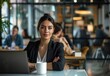 © Bambalino Studio - A woman is sitting at a table with a laptop and a cup of coffee. She is wearing a business suit and she is focused on her work
