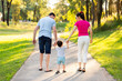 © Austockphoto - Family of three holding hands with toddler on suburban walk in afternoon light
