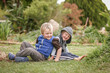 © Austockphoto - Happy little boys sitting back to back on the lawn