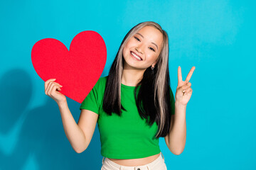 Wall Mural - Photo of nice young girl heart card v-sign wear green t-shirt isolated on teal color background