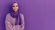 © dewaai - A portrait of a young smiling Muslim woman wearing a purple hijab against a purple background studio with copy space for text