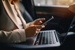 © alisaaa - Close-up of businesswoman using smart phone and laptop while commuting to work in a car. Close-up of businesswoman texting on mobile phone while working on laptop on backseat of a car.