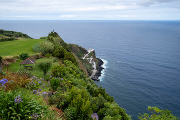 Wall Mural - The historic Arnel lighthouse on top off a cliff and steep access road along fisherman homes down to the harbor