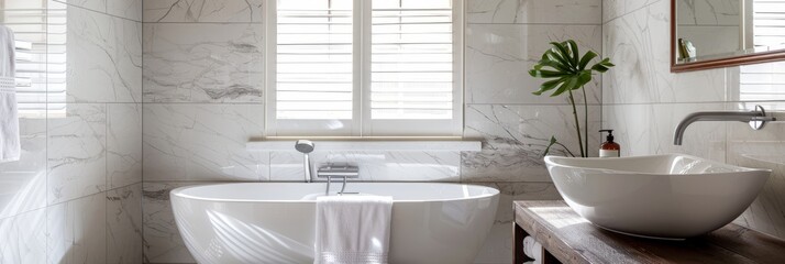 A sleek, modern bathroom featuring white marble tiles, a spacious tub with a towel draped over the edge, and a sleek, white sink with copy space on the right side