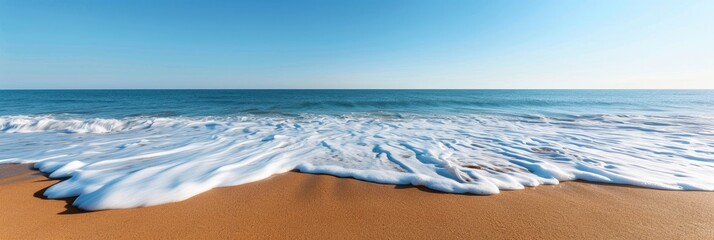 Poster - A beautiful image of ocean waves gently crashing onto a sandy beach on a bright and clear day. The vast ocean stretches out under a blue sky