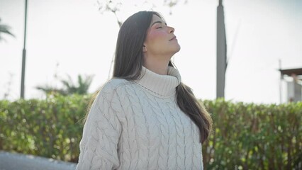 Poster - A serene woman in a white sweater enjoys the tranquility of a lush park.