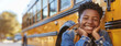 © LightoLife - Wide-angle shot of a cheerful African American teenage boy, student, grinning happily, posed next to a classic yellow school bus