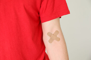 Wall Mural - Blood donation. Woman with sticking plaster on her arm against gray background, closeup. Space for text