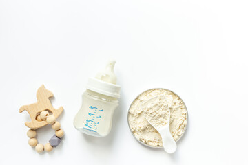 Wall Mural - Milk for baby in a bottle with powdered milk in a spoon on white background, top view