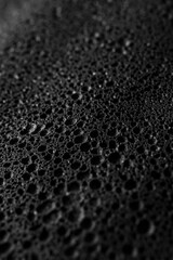 Sticker - Close-up view of water droplets on a black surface, suitable for use in science or technology contexts