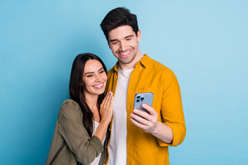 Wall Mural - Photo of two nice young partners hug use phone wear shirt isolated on blue color background
