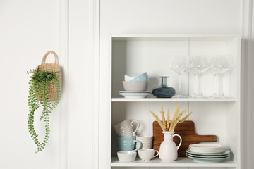 Wall Mural - Different clean dishware and glasses on shelves in cabinet indoors