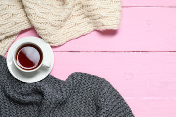 Wall Mural - Knitted scarfs and tea on pink wooden table, flat lay. Space for text