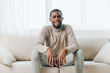© SHOTPRIME STUDIO - Stressed African American man with a headache sitting alone on a couch in his apartment The tired and sick guy appears depressed and unhappy, showing signs of physical and mental exhaustion The image
