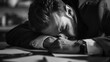 © Jelena - exhausted overworked businessman resting head on desk feeling stressed and overwhelmed dramatic black and white photo