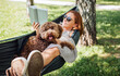 © Soloviova Liudmyla - Woman reading book relaxing in hammock with her fluffy brown Maltipoo dog on sunny day. Both looking content and happy. This outdoor scene captures joy of bonding with pets and enjoying togetherness