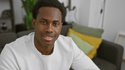 Wall Mural - A young black man in a white shirt smiling in a modern living room