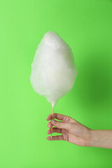 Poster - Woman holding sweet cotton candy on light green background, closeup