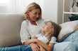 © SHOTPRIME STUDIO - Mother and daughter sharing a tender moment on a cozy couch in a warmly lit living room