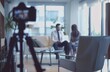© pham - A camera on a tripod records an interview with a couple sitting on a white sofa in a modern living room