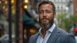 © svastix - A distinguished man with a grey beard and a warm smile, dressed in a sharp suit, poses in an urban setting, blending modern style with timeless elegance against a street backdrop.