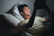 © wdnld - Young man using tablet in bed at night