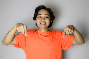 portrait of an asian indonesian young man wearing a orange shirt with a random expression when photo