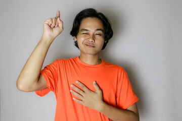 Portrait of an Asian Indonesian young man wearing a orange shirt with a random expression when photographed with an isolated white background