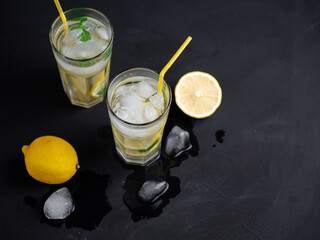 Wall Mural - homemade refreshing summer lemonade with lemon, mint and ice , black background, copy space
