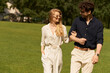 © LIGHTFIELD STUDIOS - A beautiful young couple in elegant clothing walks together on a green field, embodying a luxurious, old-money lifestyle.