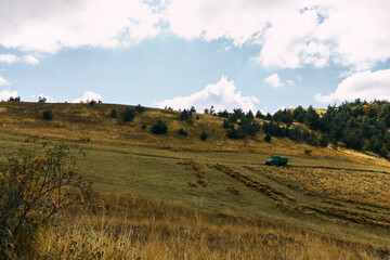 Rural landscape with vintage tractor surrounded by green fields and trees in background, agriculture and travel concept