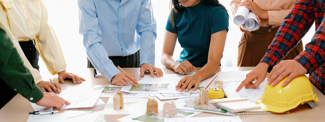Wall Mural - Professional architect engineer team discussion about architectural project on meeting table with wooden block and blueprint scatter around. Design and cooperate concept. Closeup. Delineation.