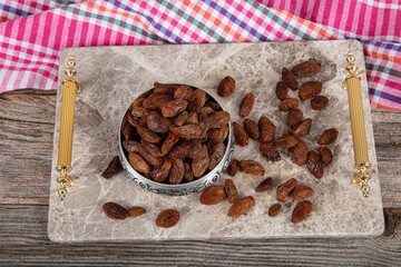 Wall Mural - Yellow raisins with seeds. Dried yellow raisins in a copper bowl served on a marble tray, raisins scattered around a copper bowl of raisins.