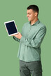 © Pixel-Shot - Young man with blank tablet computer on green background. Online dating concept