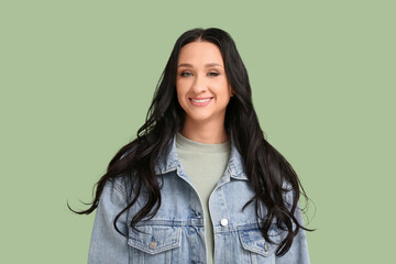 Canvas Print - Beautiful young woman with dark wavy hair in denim jacket on green background