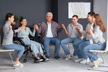 Poster - Mature woman in wheelchair with people holding hands at group therapy session