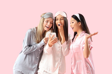 Poster - Young women in pajamas using mobile phone on pink background. Hen Party