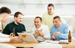 © JackF - Group of joyful friends watching football match on a laptop together and drinking beer