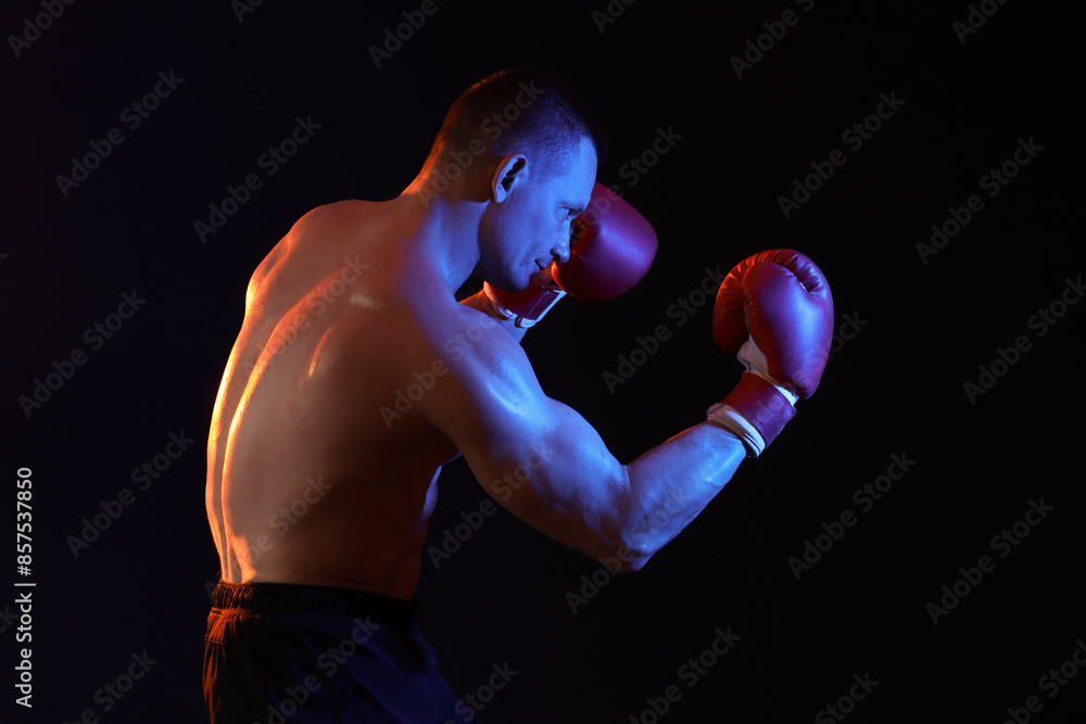Muscular man in boxing gloves on dark background