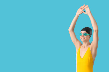 Wall Mural - Happy young female swimmer on blue background