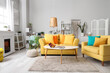 © Pixel-Shot - Interior of living room with yellow sofa, fireplace and plants