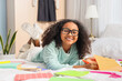 © Pixel-Shot - Little African-American schoolgirl with copybook studying in bedroom