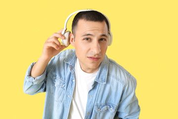 Sticker - Handsome young suspicious man in headphones on yellow background