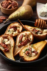 Wall Mural - Delicious baked pears with nuts, blue cheese and honey on wooden table, closeup